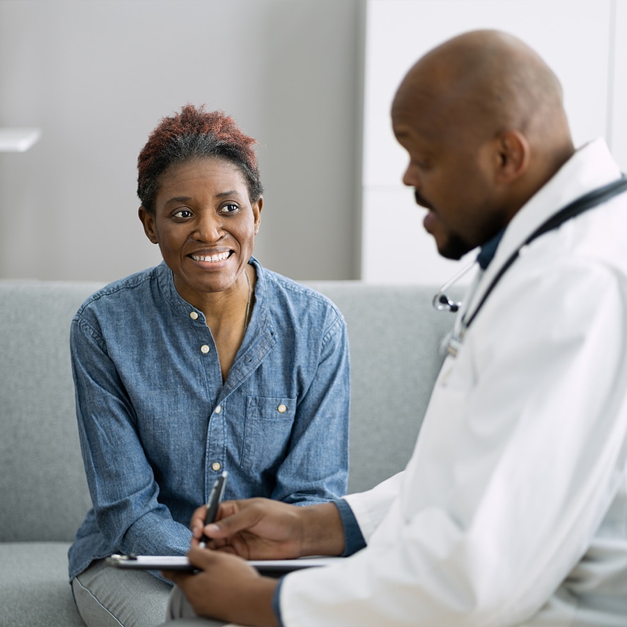 black bald doctor talking with black woman in jean shirt